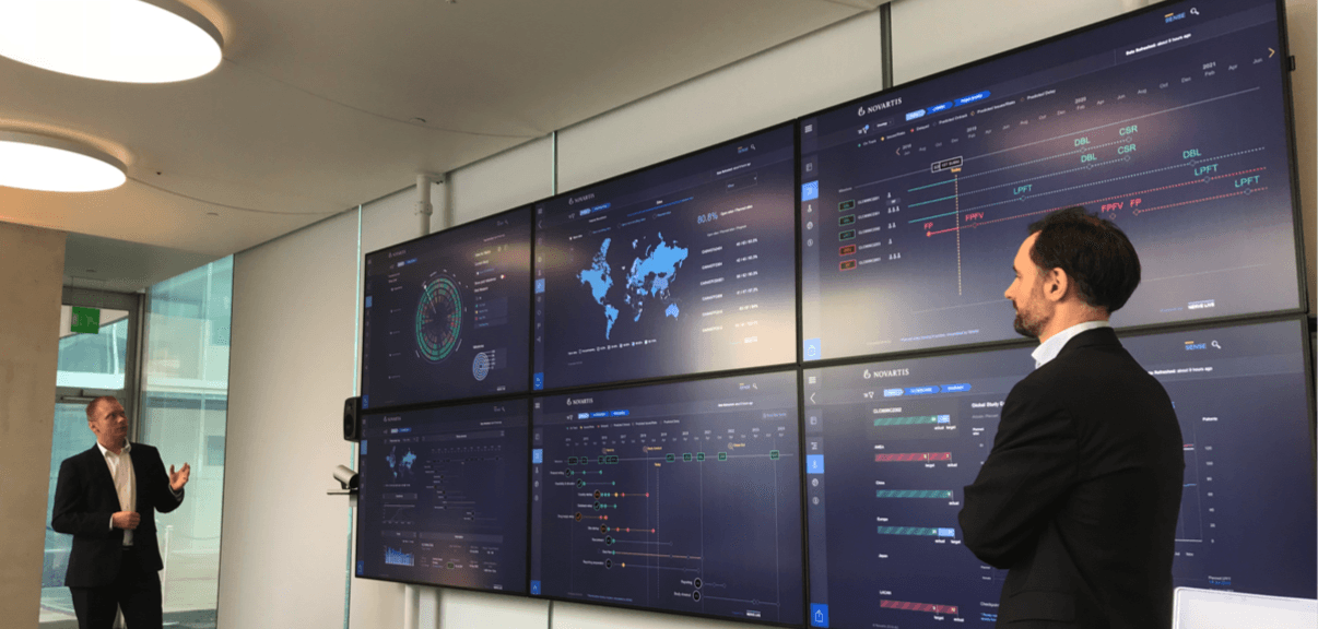 A portfolio director briefing colleagues in front of the SENSE Bridge wall of screens